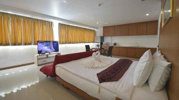 Una habitación de hotel moderna con una cama grande, televisión, escritorio y kitchenette.