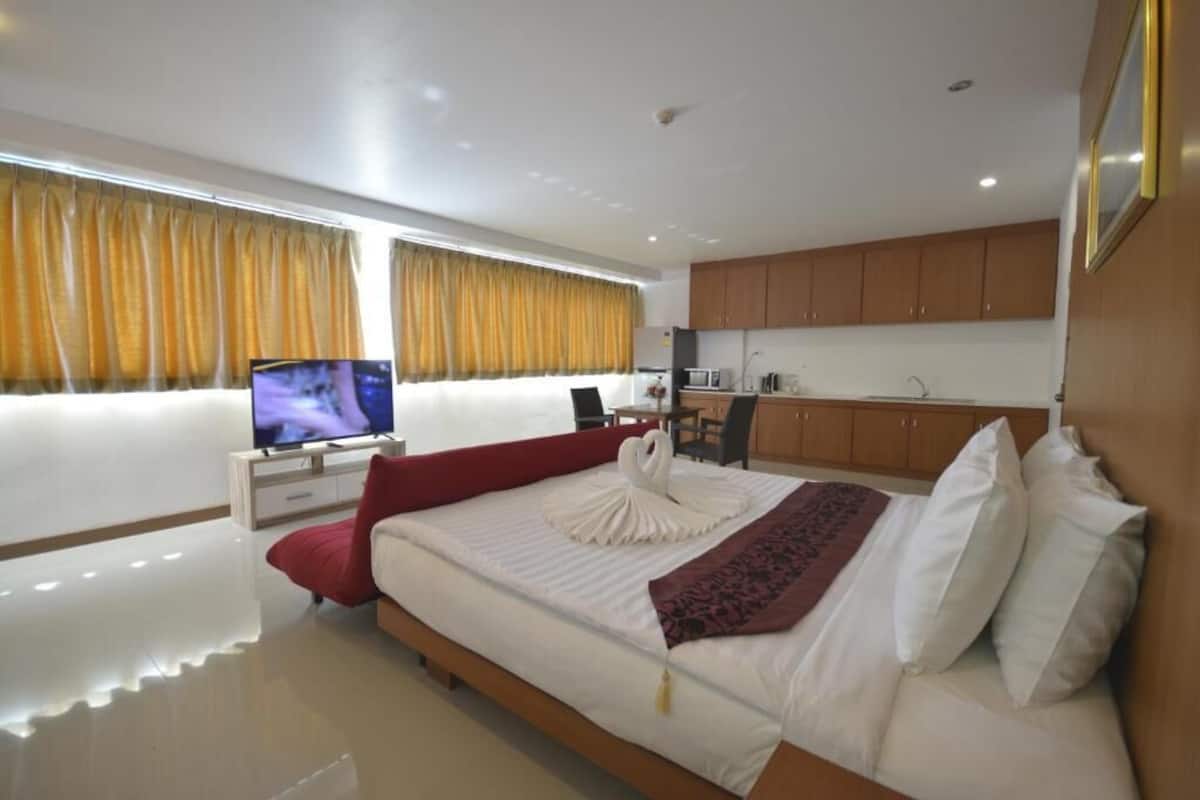 Ein modernes Hotelzimmer mit einem großen Bett, einem Fernseher, einem Schreibtisch und einer Küchenzeile.