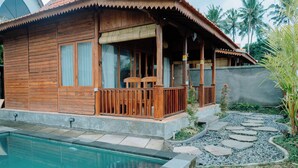Una casa de madera con piscina, un porche con sillas y un sendero de piedra.