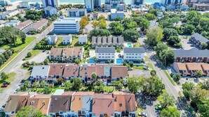 An aerial view of a coastal residential area with various buildings, including multi-story structures and single-family homes, alongside a beachfront. - Driftwood Days Pet Friendly Beach Home (Myrtle Beach)