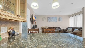 A spacious living area with a large island, wooden cabinets, and a dining table. - Driftwood Days Pet Friendly Beach Home (Myrtle Beach)