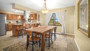A kitchen with wooden cabinets, a central island, and a dining area with a table and chairs. - Nature's Sanctuary-3 Mi to Downtown Eureka Springs (Eureka Springs)