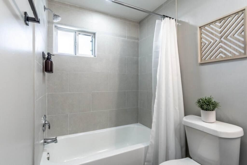 Un baño moderno con bañera, cortina de ducha y un ventanal.