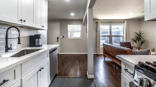 A modern kitchen with white cabinets, a black faucet, and a built-in oven. - Stylish 1BR Urban Retreat (Houston)