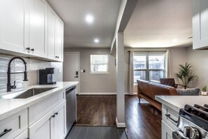 A modern kitchen with white cabinets, a black faucet, and a built-in oven. - Stylish 1BR Urban Retreat (Houston)