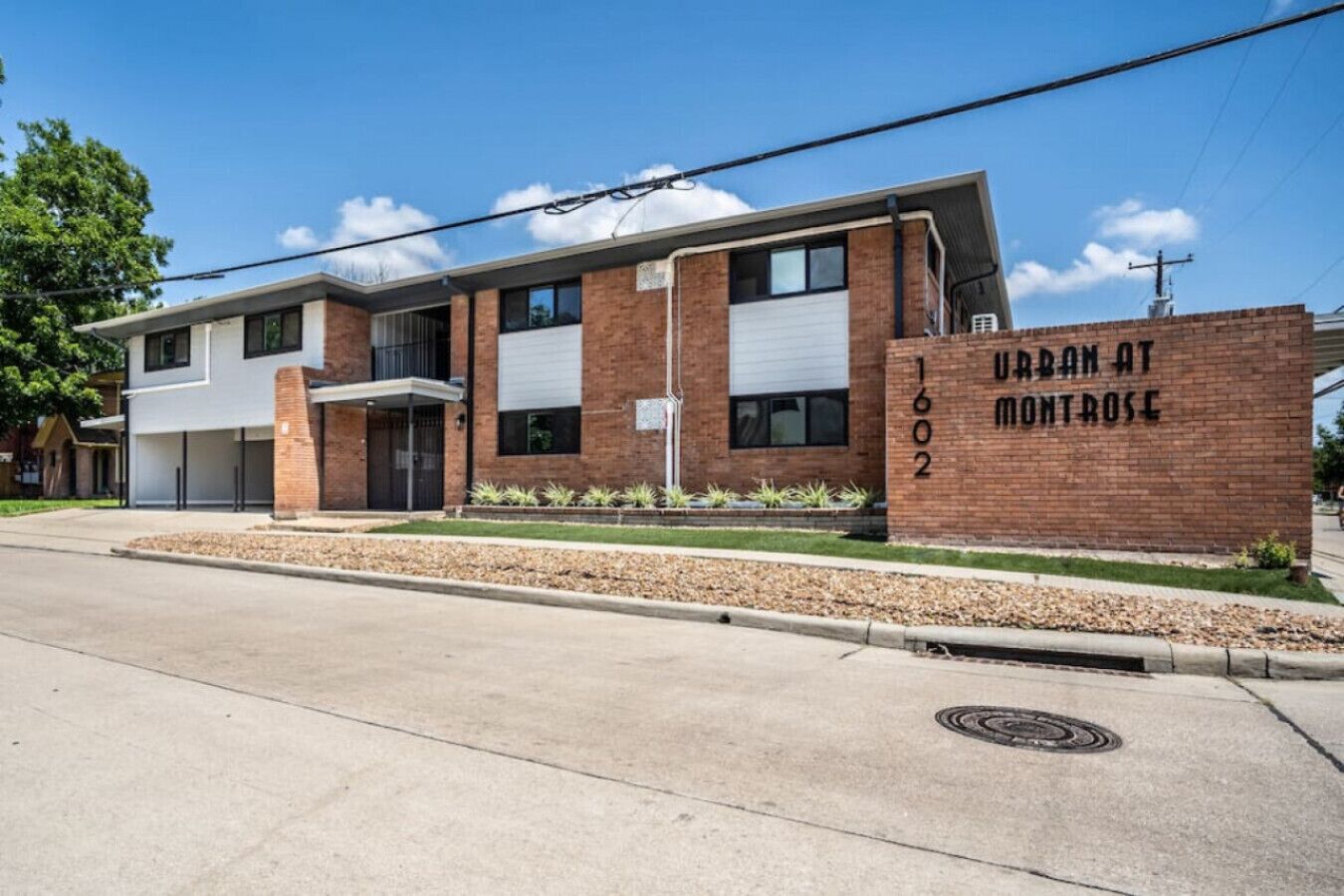 Un immeuble de deux étages avec une façade en briques, un garage et une enseigne indiquant « URBAN AT MONTROSE 602 ».