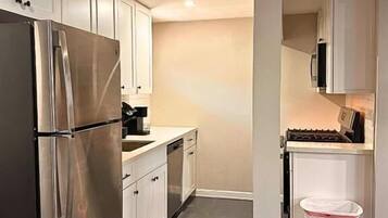 Una cocina moderna con electrodomésticos de acero inoxidable, armarios blancos y piso de madera.