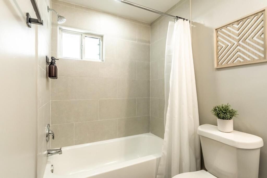 A modern bathroom with a bathtub, shower, and toilet.
