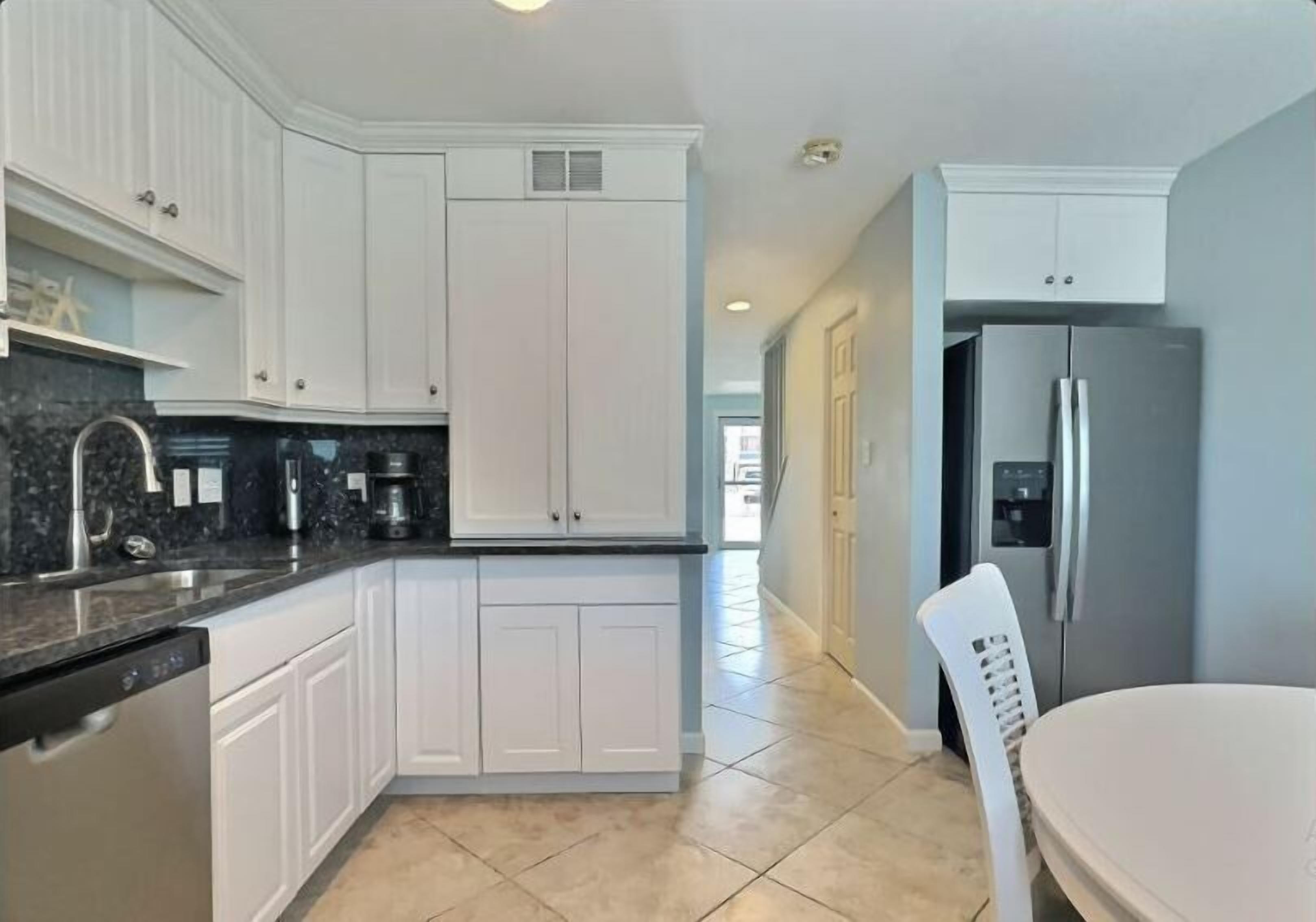 A modern kitchen with white cabinetry, a stainless steel refrigerator, and a dishwasher.
