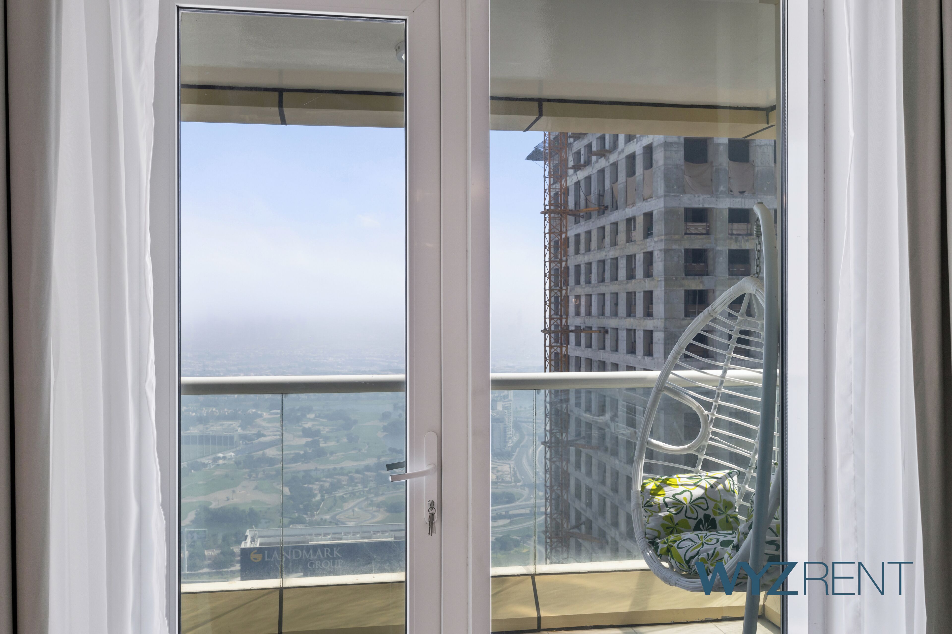 Un balcone con vista sulla città e una gru edile.