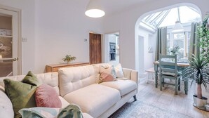 Ein modernes Wohnzimmer mit einer Couch, einem Esstisch mit Stühlen und einem großen Fenster, das für natürliches Licht sorgt.