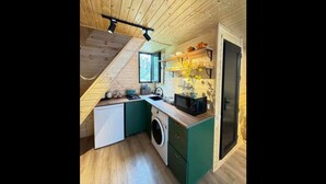 Une cuisine de taille réduite avec des poutres en bois, un lave-linge et un four à micro-ondes.