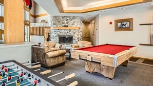 A pool table, a foosball table, a stone fireplace, and a cozy seating area with leather chairs. - Pet Friendly Studio Cross Creek Condo - CC102A (Frisco)