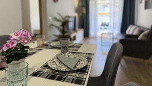 A dining area with a table set for two, a vase with flowers, and a view into the living room. - Bright Salou Apartment - 2 Bedroom, Free WiFi (Salou)