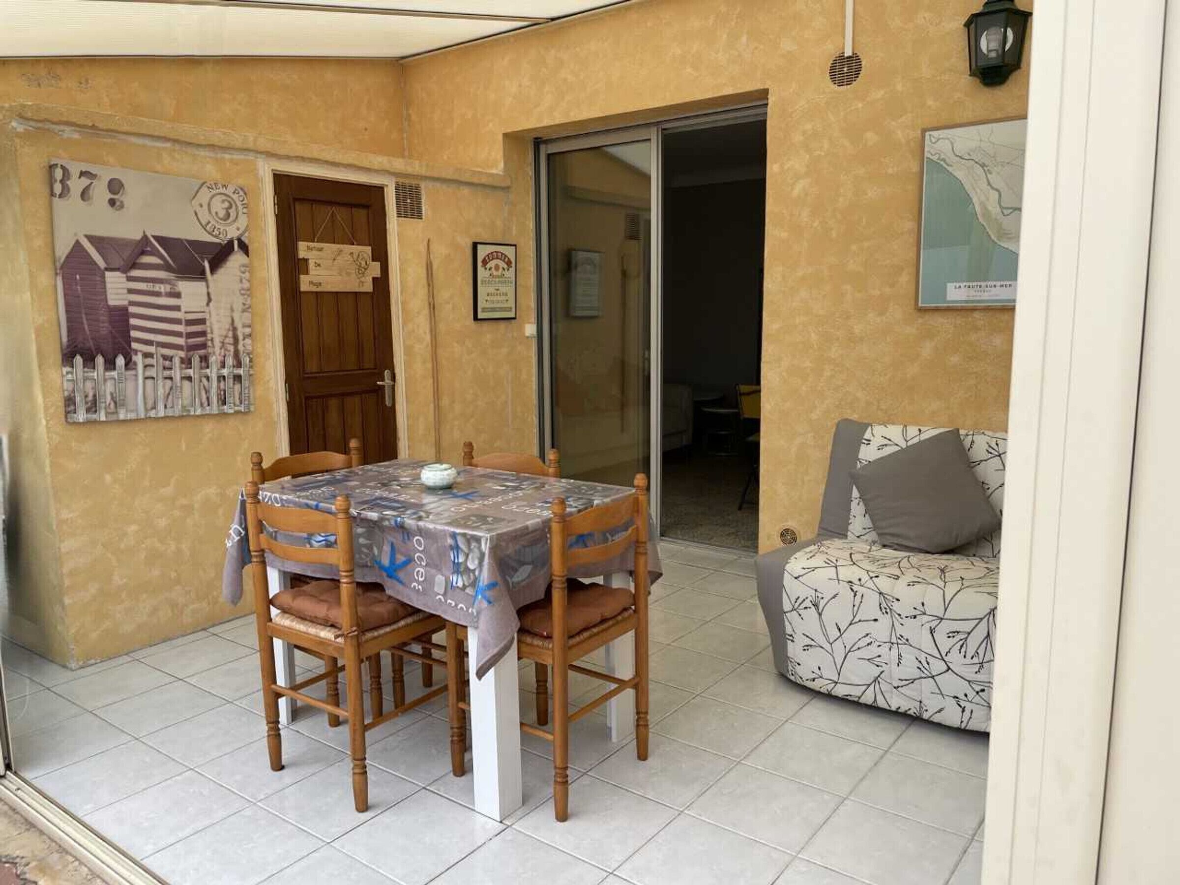A dining area with a table covered by a tablecloth, wooden chairs, and a framed picture on the wall.