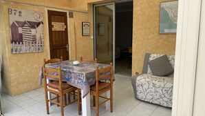Een eethoek met een tafel, een tafelkleed, houten stoelen en een lijst met een afbeelding aan de muur.