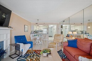 Uma sala de estar com sofá, poltronas, mesa de centro e televisão.