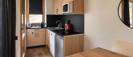 Une cuisine compacte dotée de meubles en bois, d’un four à micro-ondes, d’une bouilloire et d’un évier.
