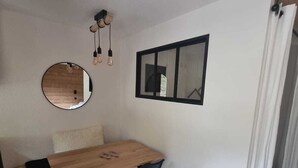 A compact room with a wooden dining table, two black chairs, a round mirror, and a black-framed window. - Renovated Studio for 4 in Plagne Bellecôte, balcony (Plagne Bellecôte)