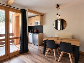 Una cocina moderna con armarios de madera, microondas y un lavabo. Hay una mesa de comedor con dos sillas y un espejo en la pared.