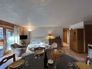 Una habitación acogedora con una cama, un televisor, una mesa de comedor para dos personas y un armario.
