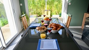 A dining table with breakfast items, wine glasses, and a view of greenery. - Modern house with garden, not overlooked – 3 bedrooms – Vannes (Vannes)