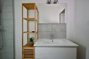A bathroom with a wooden shelf unit, a sink, and a shower. - Modern house with garden, not overlooked – 3 bedrooms – Vannes (Vannes)