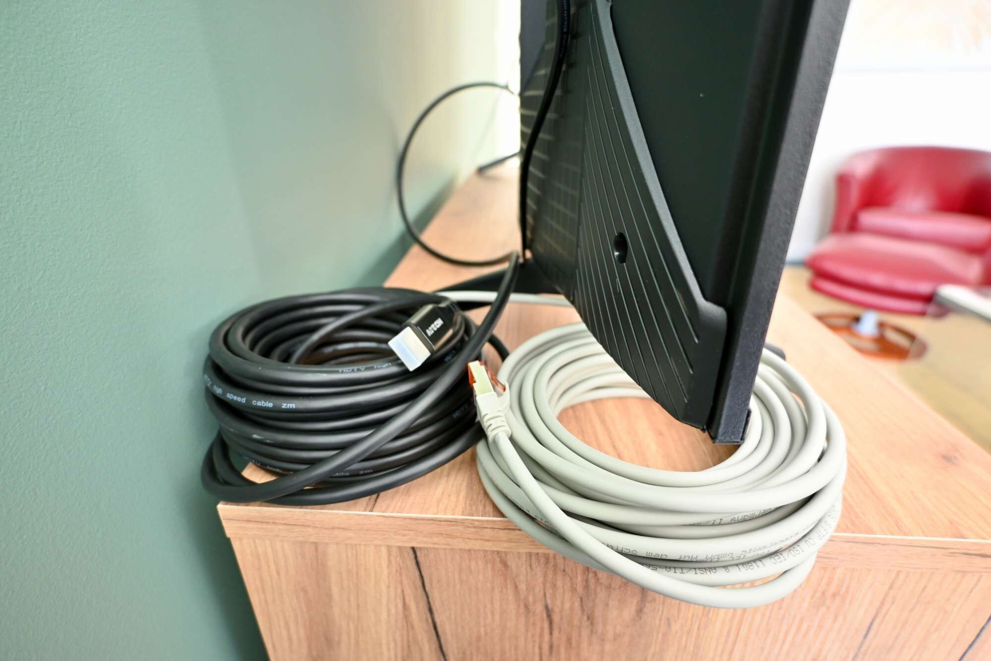 A computer monitor with a coiled black and white cable on a wooden surface.