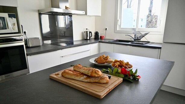 A modern kitchen with a large island, a built-in oven, and a window with a view. - Modern house with garden, not overlooked – 3 bedrooms – Vannes (Vannes)