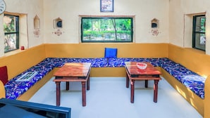 A room with a large window, a sofa, two wooden tables, and decorative wall elements. -  Sariska Forest Trail (Rajgarh)