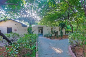 A building with a door and window, surrounded by greenery and a paved path.