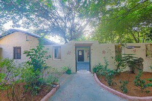 A pathway leading to a building with a reception sign, surrounded by greenery and a wall with decorative elements. -  Sariska Forest Trail (Rajgarh)