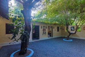 A courtyard with trees, a building with a door, and a window.