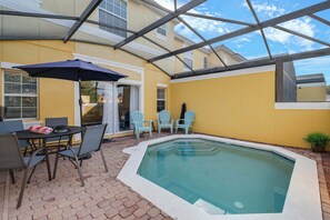 A pool area with a glass ceiling, a table with chairs, and a small patio table. - Spacious townhouse w/ pool, patio & workspace (Kissimmee)