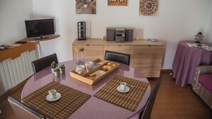 Un comedor con una mesa redonda, sillas, una máquina de café y un televisor sobre un mueble.