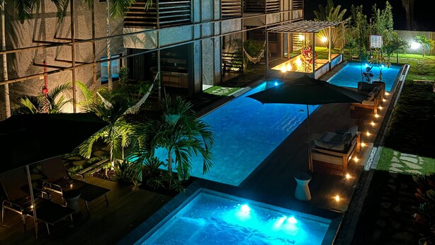 Un hôtel moderne doté d’une piscine, d’un espace extérieur aménagé et offrant une vue sur le ciel nocturne.