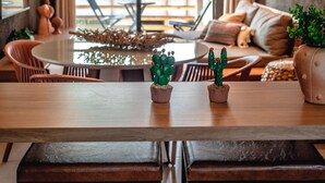 Un comedor moderno con una mesa redonda, bancos y plantas en macetas.
