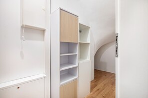 Ein weißer Kleiderschrank mit mehreren Einlegeböden und einer Holztür.