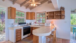 Une cuisine avec des meubles de rangement en bois, une cuisinière, un four à micro-ondes et un grand îlot central doté de tabourets de bar.