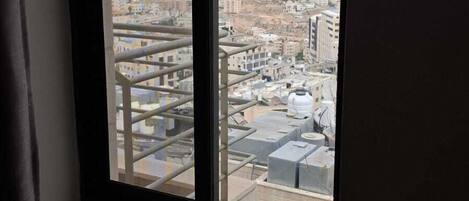 Una ventana con vistas a un paisaje urbano, que incluye edificios y una colina distante.