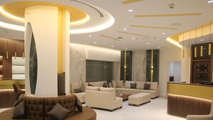 Un interior moderno con una columna central, un conjunto de sofás y un mostrador de recepción.