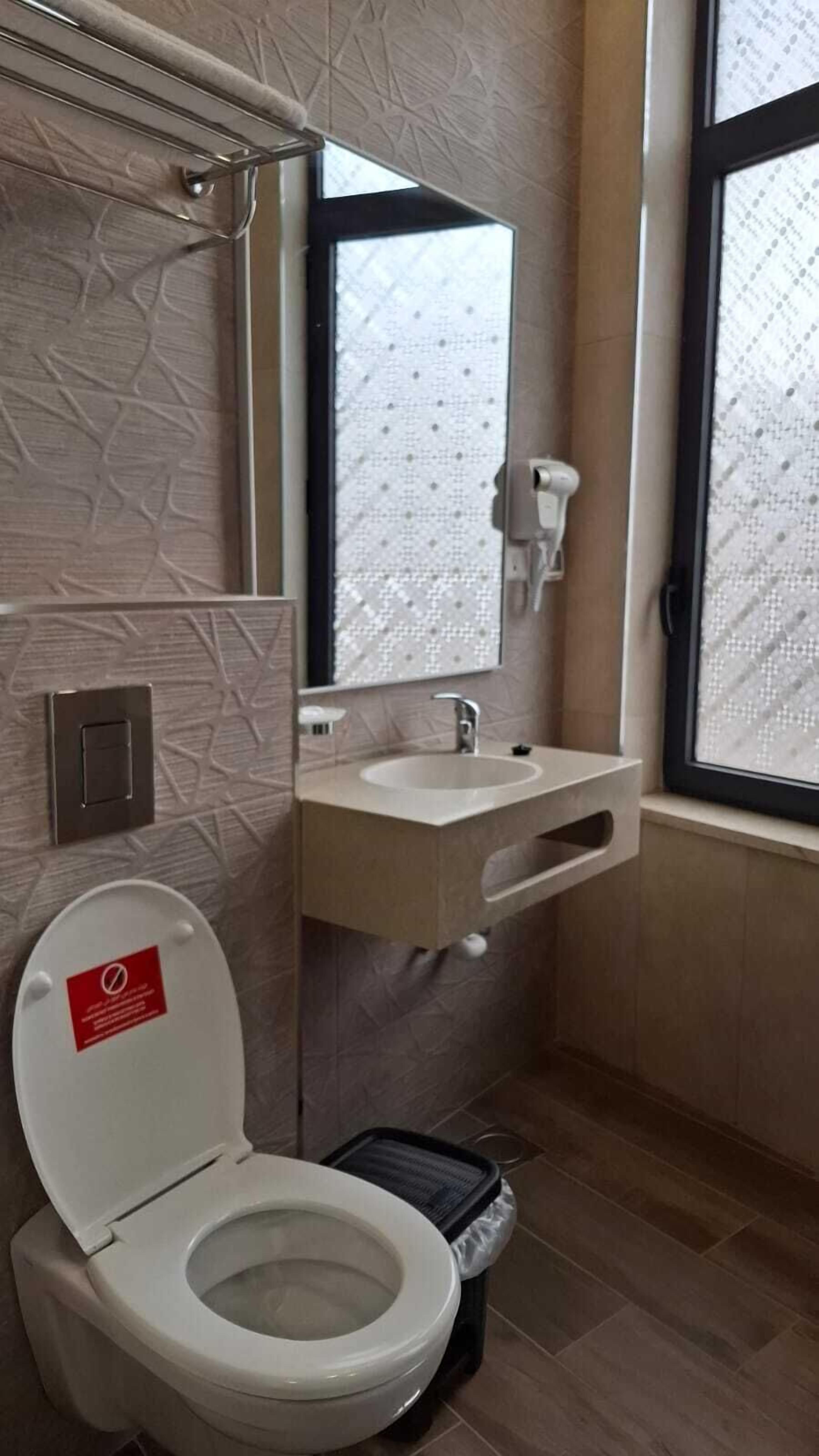 A bathroom with a toilet, sink, and window.