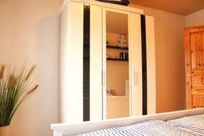 Une chambre à coucher avec un lit, une armoire et une plante en pot.