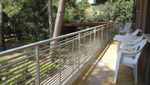 Ein Balkon mit Metallgeländer, weißen Plastikstühlen und gefliestem Boden.