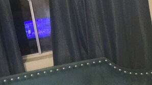 A room with a bed, a window with curtains, and a television displaying a blue screen. - Studio apartment across the street from the convention center (San Diego)