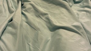 A bed with a light green blanket. - Studio apartment across the street from the convention center (San Diego)