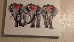 A painting of three elephants with floral decorations on their heads, mounted on a wall. - Studio apartment across the street from the convention center (San Diego)