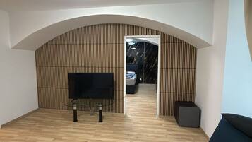 Ein modernes Wohnzimmer mit Fernseher, Holzwand und Sofa.