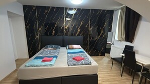 A double bed with a headboard, a desk with a chair, and a window with curtains. - Economy Souterrain 2BR - Prater Amuesement Park (Vienna)