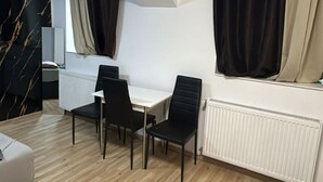 A modern room with a white table and black chairs, a radiator, and a window with curtains. - Economy Souterrain 2BR - Prater Amuesement Park (Vienna)